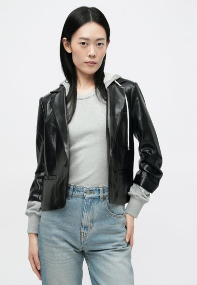 Μαύρο μπουφάν από faux δέρμα με αυλακωτές πέτο πάνω από γκρι ριγέ μπλούζα μακρύ μανίκι, συνδυασμένο με ψηλόμεσα ανοιχτό γαλάζια τζην παντελόνια.