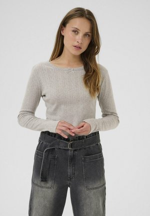 Lichtgrijs geribbeld longsleeve shirt met een ronde halslijn en een kleine strikdetail. Gecombineerd met hoge taille zwarte jeans met grote zakken en een riem.
