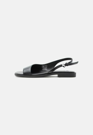 Black leather flat sandal with open toe and adjustable slingback strap on white background.