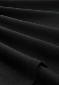 Zwarte stof met een gladde, matte textuur, gevouwen in meerdere lagen, die een gelijkmatig oppervlak en subtiele stikdetails toont.