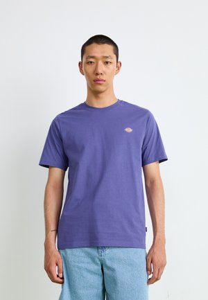 Purple cotton t-shirt with short sleeves, crew neckline, and small logo on the left chest. Paired with light blue denim shorts.