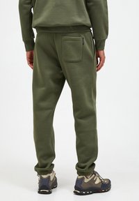 Olivenfarvede sweatpants med ribbet talje og ribbede ankler, med en baglomme og en glat stofstruktur.