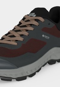 Σκούρο γκρι και κόκκινο αθλητικό παπούτσι με μπεζ κορδόνια, υφασμένη σόλα και λογότυπο Gore-Tex Invisible Fit στο πλάι.