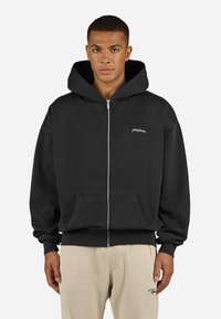 Sort zip-up hoodie lavet af en bomuldsblanding, med en kengurulomme, ribbede manchetter og kant, samt en lille broderet logo på brystet.