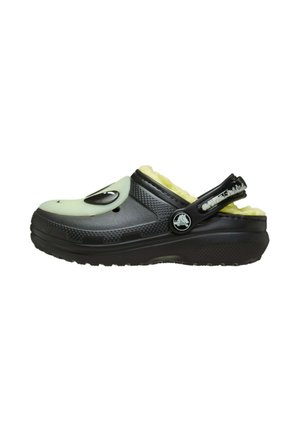 Zoccoli neri con una tomaia strutturata, caratterizzati da un accento verde chiaro e una fodera morbida. Inclusa una cinghia posteriore per un indosso sicuro.