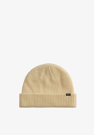 Bonnet en maille couleur crème avec revers replié et petite étiquette noire portant la mention « Vans » sur fond blanc uni.