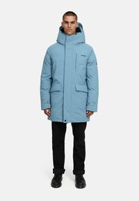 Svetlomodrá, zateplená parka s vysokým golierom a nastaviteľnou kapucňou. Obsahuje predné vrecká so zacvakávaním a zipsové vrecko na hrudi.