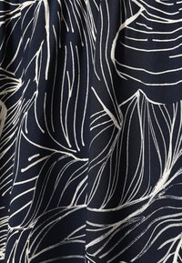 Tissu bleu foncé avec des motifs abstraits de feuilles et de lignes blanches, montrant des plis naturels et une texture douce.
