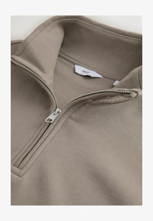 Maglione beige con mezza cerniera argentata e etichetta del marchio "NEXT" visibile all'interno del colletto.