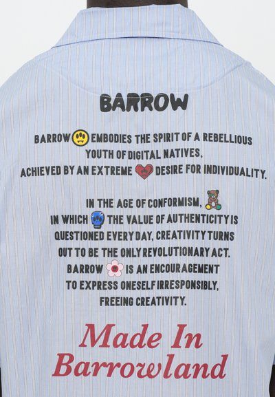 Camicia a strisce blu con testo nero e rosso e grafiche colorate. Presenta un colletto asolato e una vestibilità rilassata. Include il logo 'Made In Barrowland'.