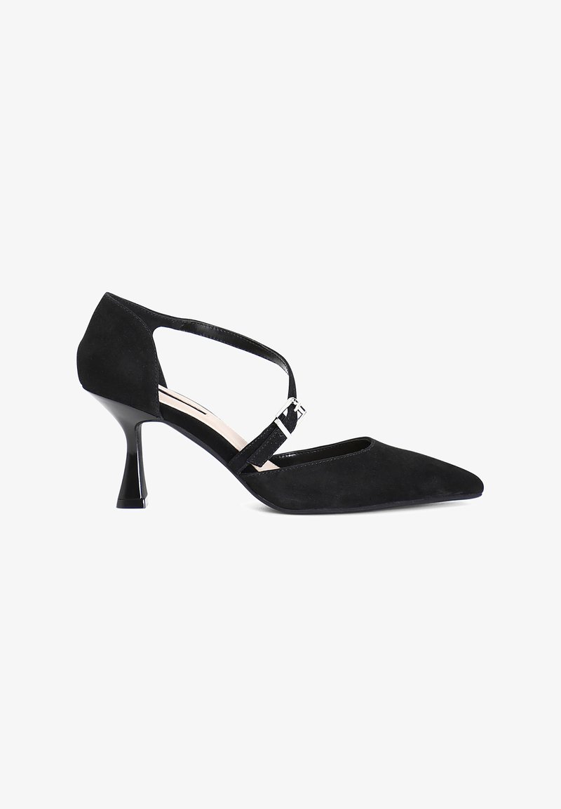 Scarpa con tacco alto in suede nero, con punta affilata, cinturino alla caviglia e un tacco scolpito unico. Presenta un accento con fibbia argentata lucida.