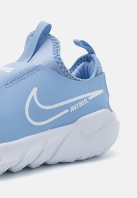 Tacco della sneaker Nike azzurro chiaro con logo swoosh bianco e testo "JUST DO IT.", con suola bianca testurizzata e linguette di estrazione.
