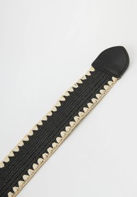 Correa tejida negra con acentos de color natural y una punta de cuero en forma de punta. Un intrincado bordado contorna los bordes de la correa.