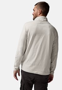 Suéter de manga larga gris claro con cuello alto, textura suave y detalles de costura mínimos, combinado con pantalones cargo oscuros.