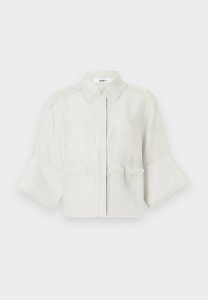 Light gray cropped shirt made of soft fabric, featuring a collared neckline, fringe detail along shoulders and hem, and wide sleeves.