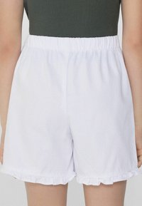 Witte katoenen shorts met een elastische tailleband en een gerimpelde zoom. De stof heeft een gladde textuur en een klassieke casual uitstraling.