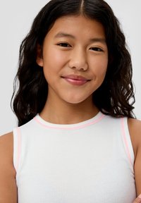 Weißes geripptes Tanktop mit pinkfarbenen Akzenten, das einen hohen Ausschnitt und ärmelloses Design aufweist. Glatte Textur, ohne sichtbare Muster.
