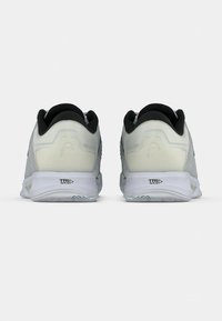 Valge sportlikud kingad musta sisepinnaga, nähtud tagant, millel on valgetel talladel "TRI N-R-G" tekst.