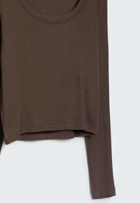 Bruin geribd shirt met lange mouwen en een ronde halslijn, met een getailleerd ontwerp en subtiele rek in de stof, met ruwe randen aan de zoom.