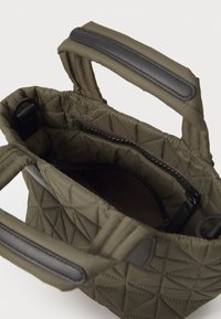 Quilted olive green bag with black leather accents, featuring dual handles, zip closure, and a textured interior with a pocket.