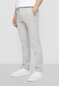 Light gray tailored pants with a textured fabric, featuring front pockets and a slim fit. Paired with white sneakers for contrast.