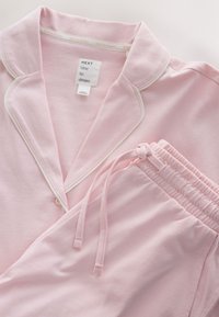 Set de pijama roz pal cu tivitură albă pe guler și nasture, pantaloni cu talie elastică și șnur, eticheta spune "Next time to dream"