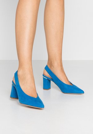 Talons slingback en suede bleu avec un bout pointu et un talon bloc. Le design présente une découpe au niveau du talon pour un confort supplémentaire.