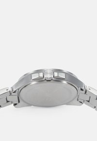 Edelstahl-Uhr mit rundem Gehäuse, prominenter Krone und silberfarbener Armbanduhr. Glatte, gebürstete Oberfläche ohne sichtbare Markierungen auf der Rückseite.