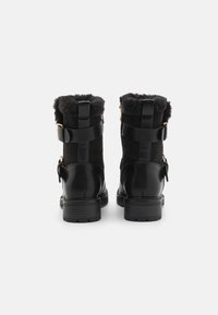 Svarta ankelstövlar med texturerad mockaöverdel, fuskpälskant och släta läderdetaljer. Inkluderar dekorativt guldfärgat metalldekor och stadiga sulor.