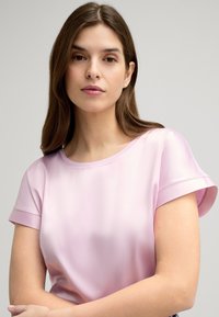 Lichtroze blouse met korte mouwen, een gladde textuur en een ronde halslijn. Kenmerkt zich door opgerolde manchetten en een zachte glansafwerking.