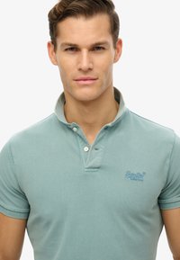 Polo shirt azzurro chiaro realizzato in tessuto texturizzato, con colletto a due bottoni e logo ricamato sul petto. Maniche corte.