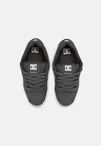 Gray athletic shoes with textured fabric and smooth synthetic accents. Features flat laces, perforated toe, and logo on tongue.