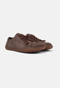 Scarpe in pelle marrone scuro con punta arrotondata, lacci frontali e cuciture a contrasto. Suola in gomma flessibile con dettagli a trama.