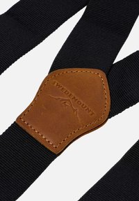 Patch en cuir marron embossé avec "SWEDEMOUNT" et logo de montagne, fixé à des sangles en tissu élastique noir.