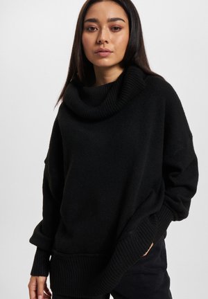 Black knitted sweater with a large fold-over collar, wide sleeves, and ribbed cuffs. Features a relaxed fit and soft texture.