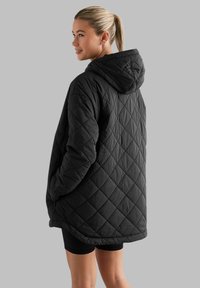 Gequilted zwarte jas met een capuchon, met een losse pasvorm en ruitpatroon. Gemaakt van een gladde stof, met een middellange ontwerp en zijzakken.