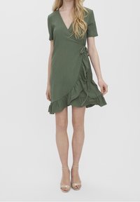 Robe portefeuille verte à manches courtes, avec un ourlet à volants et un détail noué à la taille. Confectionnée en tissu texturé.