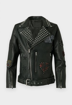 Giacca da biker in pelle nera con borchie argentate sui risvolti e sulla cintura, numerosi patch ricamati e maniche e tasche con zip.