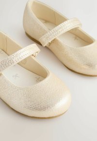 Goldfarbene Ballerinas mit strukturiertem Obermaterial, abgerundeten Zehen und einem Riemen über dem Spann. Weiches Innenfutter mit gemustertem Fußbett.