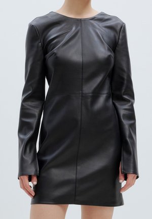 Schwarzes Lederkleid mit langen Ärmeln, runder Halslinie, taillierter Silhouette und sichtbaren Nähdetails, glatte Textur, minimalistisches Design.