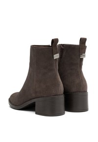 Stivaletti ankle in suede marrone con punta tonda, zip laterale e tacco spesso e texture. Presentano un piccolo logo metallico sul retro.