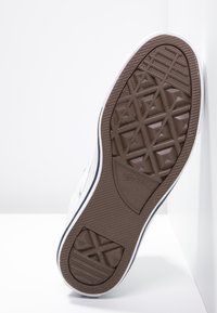 Talpa de sneaker alb din cauciuc cu o bază texturată de culoare maronie, având modele geometrice și un logo. Marginita cu bleumarin pe lateral.