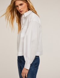 Witte button-up blouse met een klassieke kraag, lange mouwen en een enkele borstzak. Gemaakt van soepel materiaal met een comfortabele pasvorm.