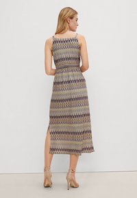 Maxikleid mit einem mehrfarbigen Zickzackmuster, enganliegendem Oberteil und seitlichem Schlitz, aus leichtem Stoff gefertigt, mit dünnen Trägern und lockerer Passform.