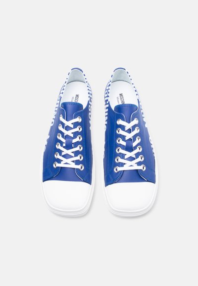 Μπλε χαμηλά αθλητικά παπούτσια με λευκά κορδόνια, λευκές άκρες μύτης και λευκό κείμενο στα πλαϊνά, εμφανιζόμενα από πάνω σε ανοιχτό φόντο.