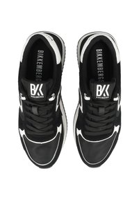 Schwarz-weiße Sportschuhe bestehen aus einer Kombination von glatten und strukturierten Materialien, besitzen ein Schnürdesign und verfügen über ein Logo auf der Zunge.