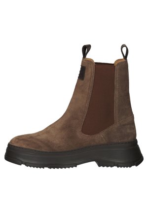 Bota Chelsea de ante marrón con panel lateral elástico, suela gruesa negra y lengüetas en el cuello del tobillo.