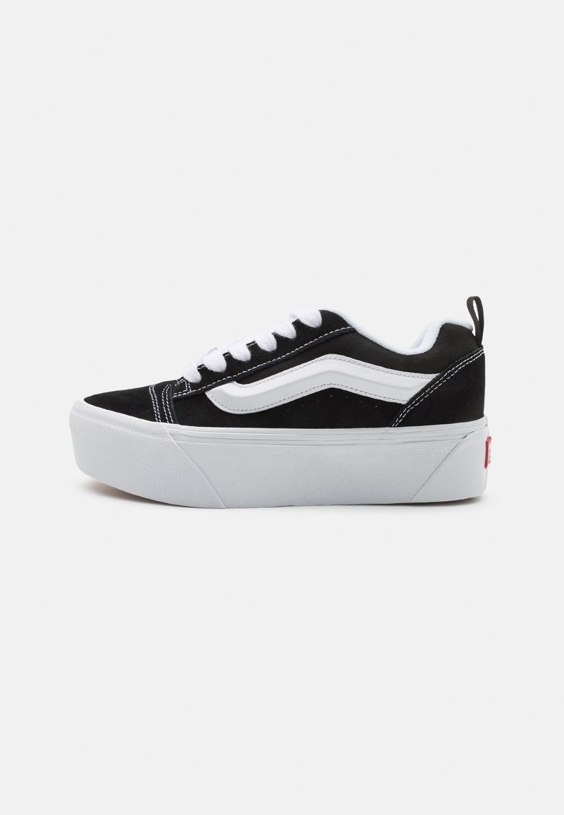 Must mustade sneakers valgete aktsentidega, paks valge tallaga, lipsudega disain ja eristuv külgtriip.