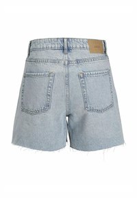 Ljusblå denimshorts med franskant, två bakfickor och en brun etikett med texten "JJXX" vid midjan. Enkel och avslappnad design.
