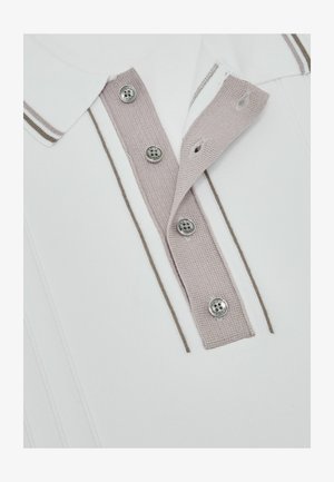 Fehér galléros póló bézs kötött gombsorral, négy fém gombbal és a galléron, valamint a póló testén megegyező bézs csíkokkal.